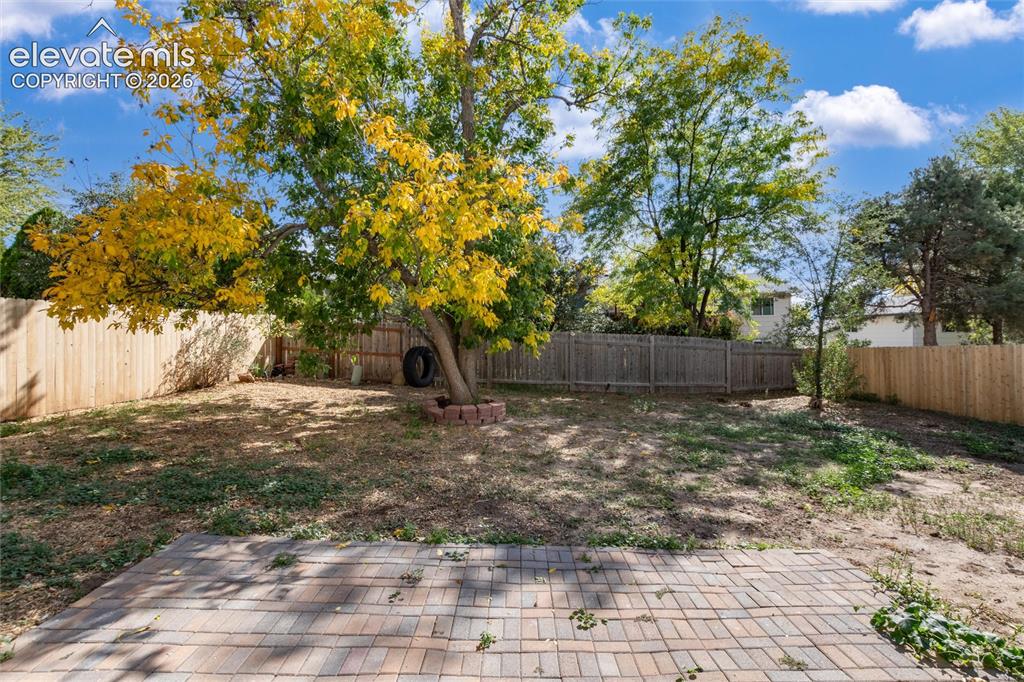 Image 37 of 47: Expansive outdoor space featuring a paver patio, established trees, and woo