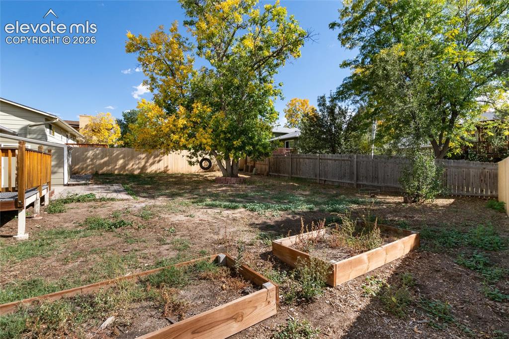 Image 38 of 47: Expansive backyard featuring mature trees, wooden privacy fencing, a wood d