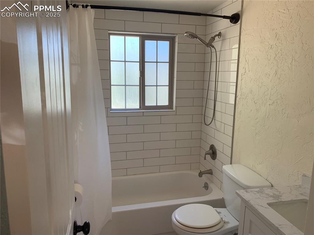 Image 17 of 32: Full bath featuring a textured wall, shower / bath combo with shower curtai