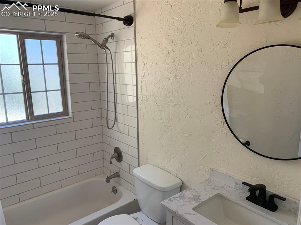 Image 18 of 32: Full bath featuring a textured wall, bathtub / shower combination, and vani