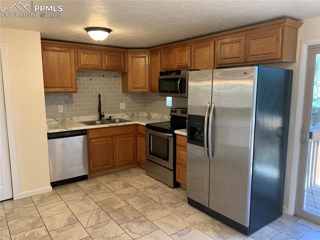 Image 2 of 32: Kitchen with stainless steel appliances, decorative backsplash, brown cabin