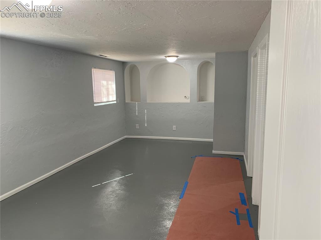Image 21 of 32: Empty room with finished concrete flooring, a textured ceiling, a textured 