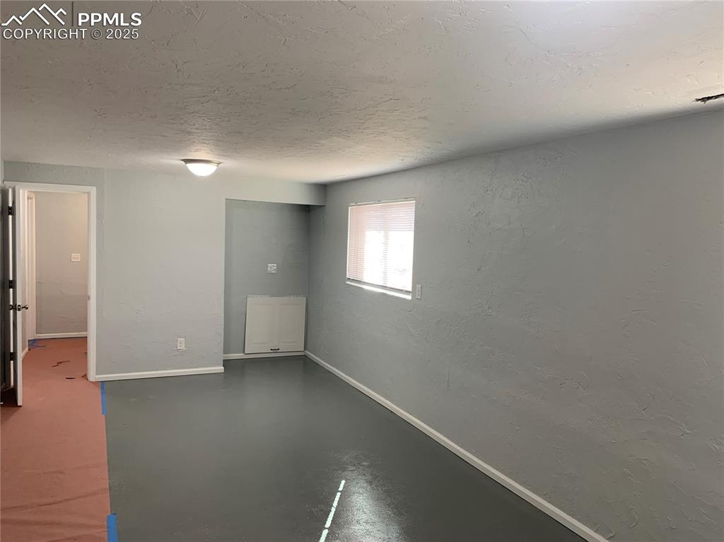 Image 22 of 32: Spare room with a textured wall, concrete floors, and a textured ceiling