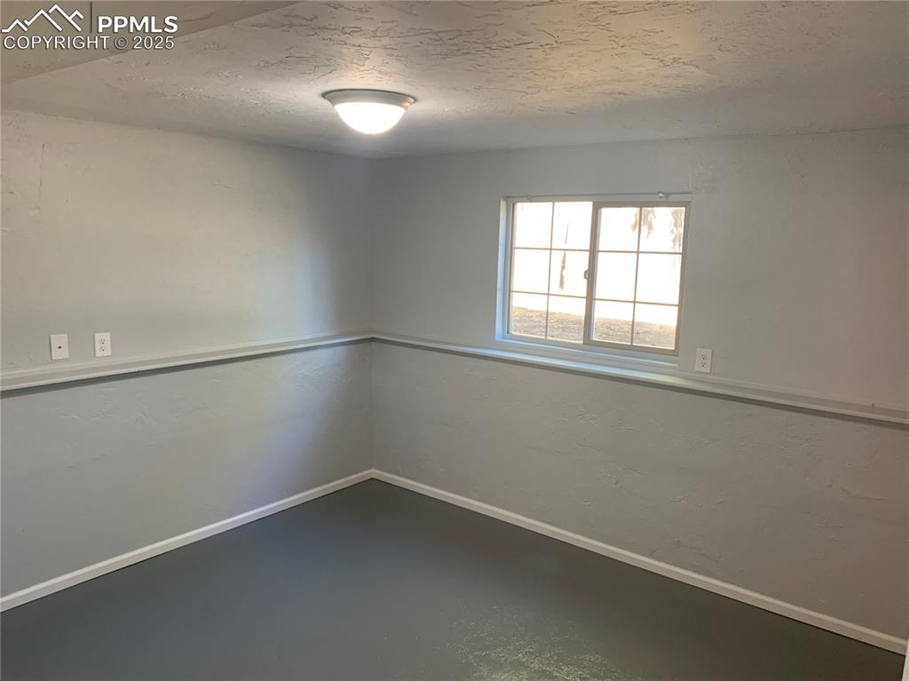 Image 24 of 32: Empty room with concrete flooring, a textured ceiling, and a textured wall