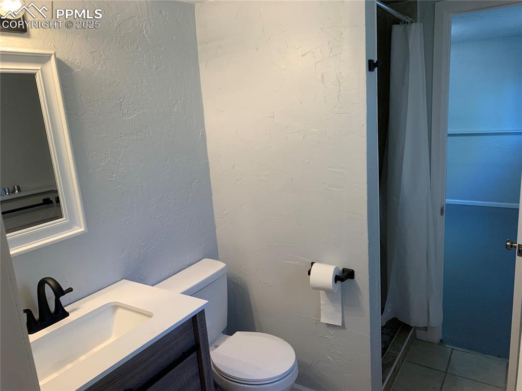 Image 28 of 32: 3/4 Bathroom featuring a textured wall, a stall shower, vanity, and tile pa