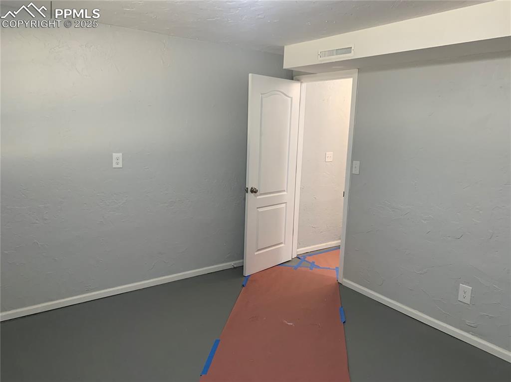 Image 29 of 32: Empty room with a textured wall, a textured ceiling, and concrete floors