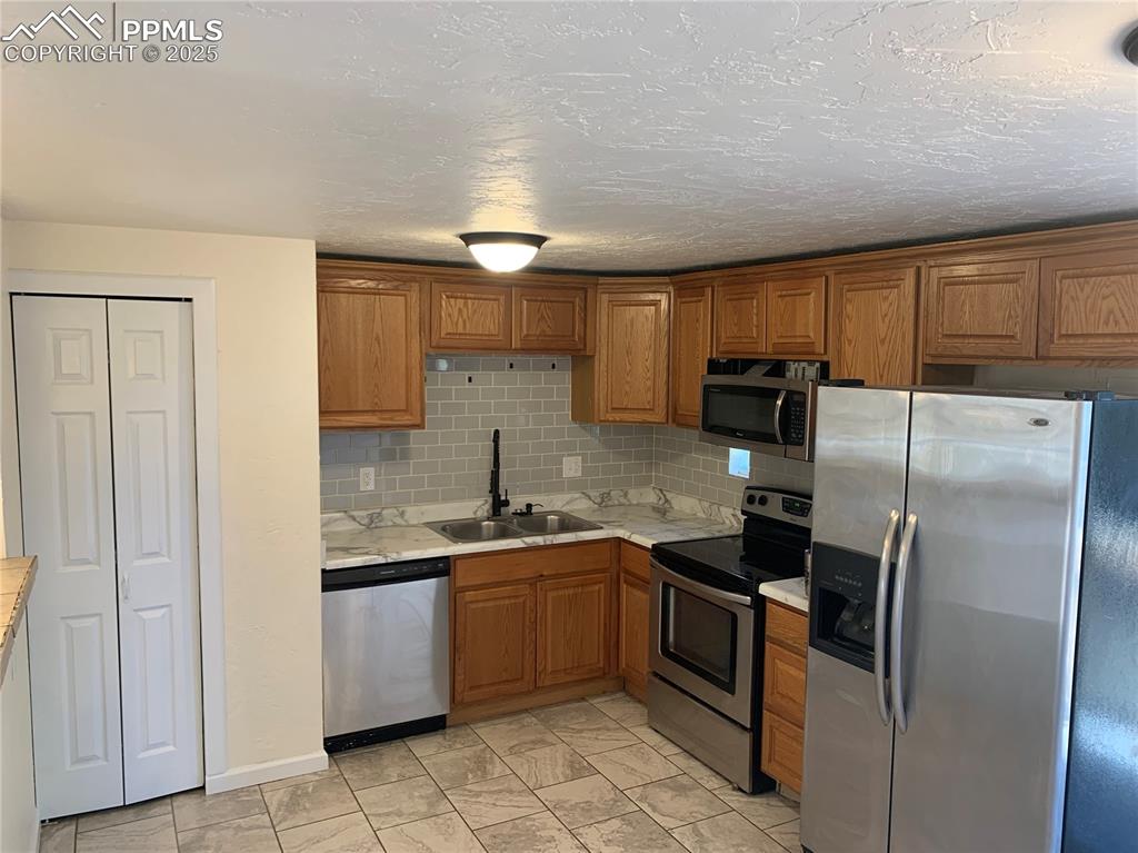 Image 4 of 32: Kitchen with appliances with stainless steel finishes, tasteful backsplash,