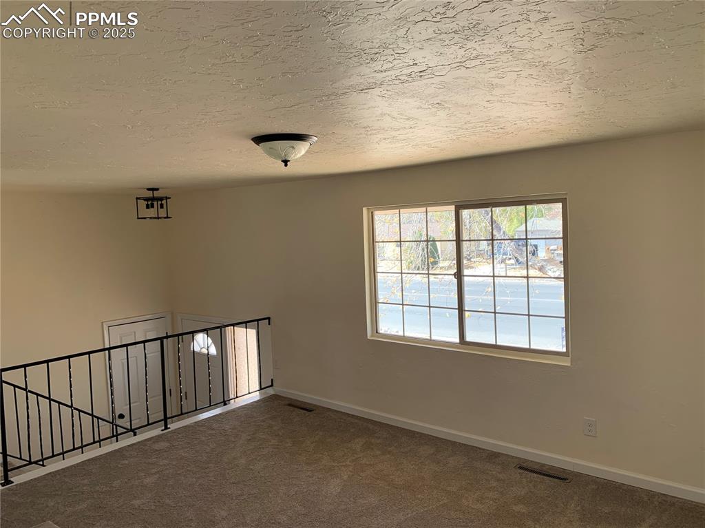 Image 5 of 32: Unfurnished room with carpet and a textured ceiling
