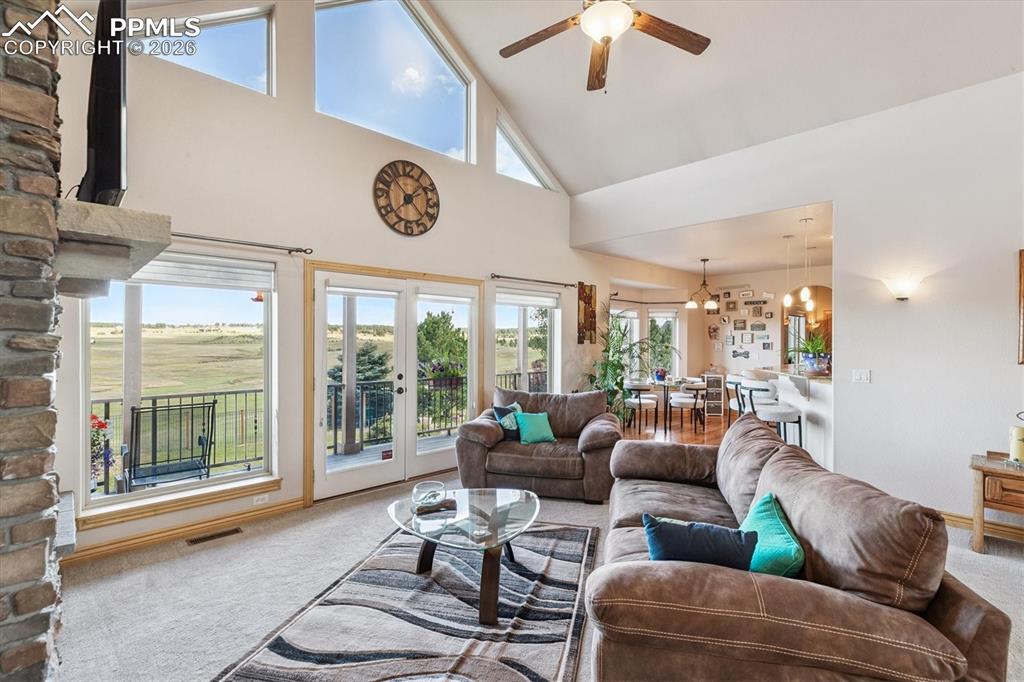Image 10 of 32: Living area with carpet flooring, high vaulted ceiling, french doors, a cha