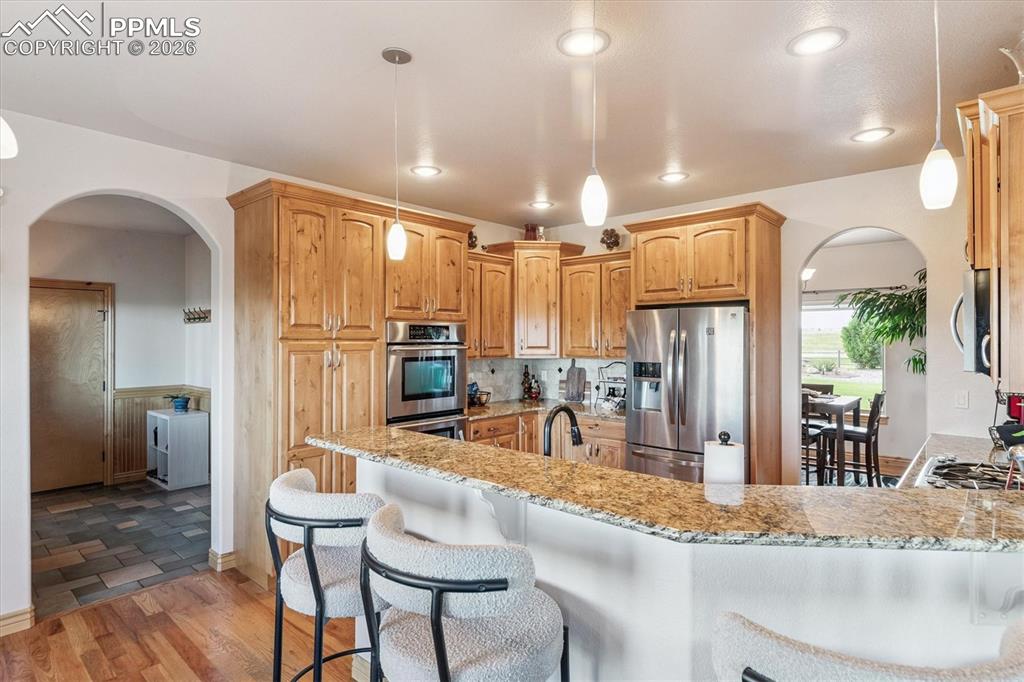 Image 12 of 32: Kitchen featuring SS appliances, pendant light fixtures, a breakfast bar ar