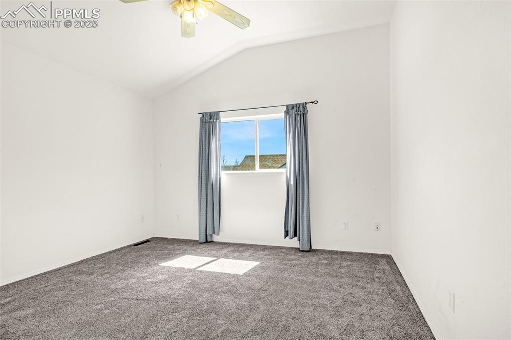 Image 11 of 17: Empty room featuring vaulted ceiling, carpet, and a ceiling fan