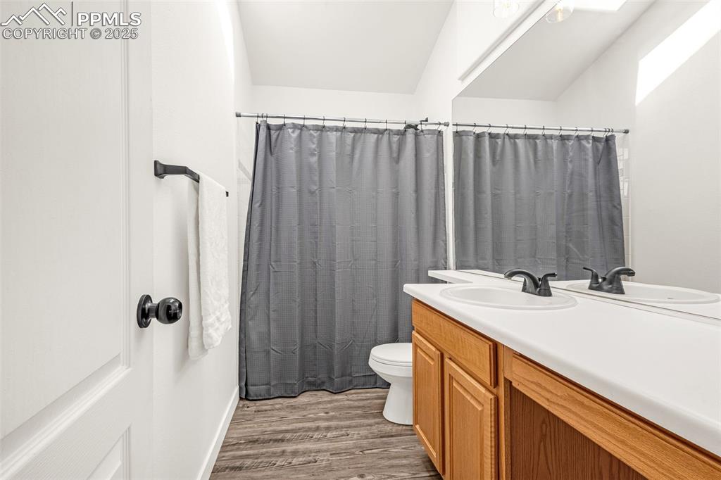 Image 12 of 17: Bathroom featuring a shower with curtain, toilet, vanity, and wood finished