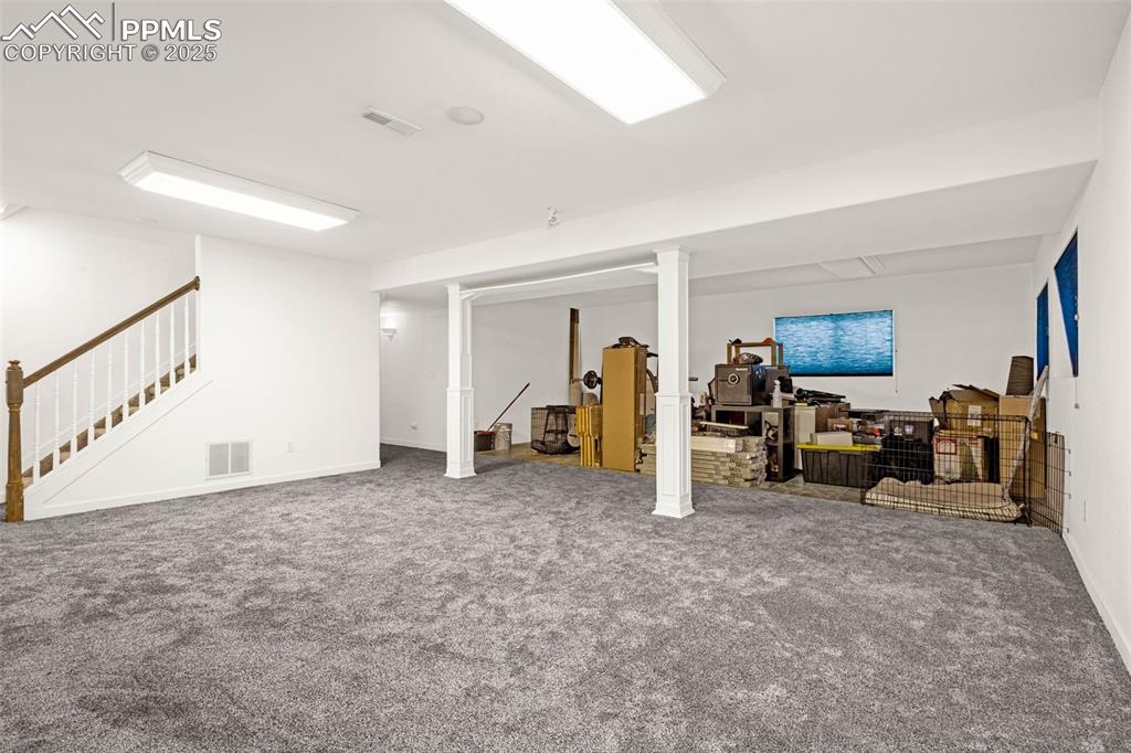 Image 13 of 17: Finished below grade area featuring stairs, visible vents, and carpet