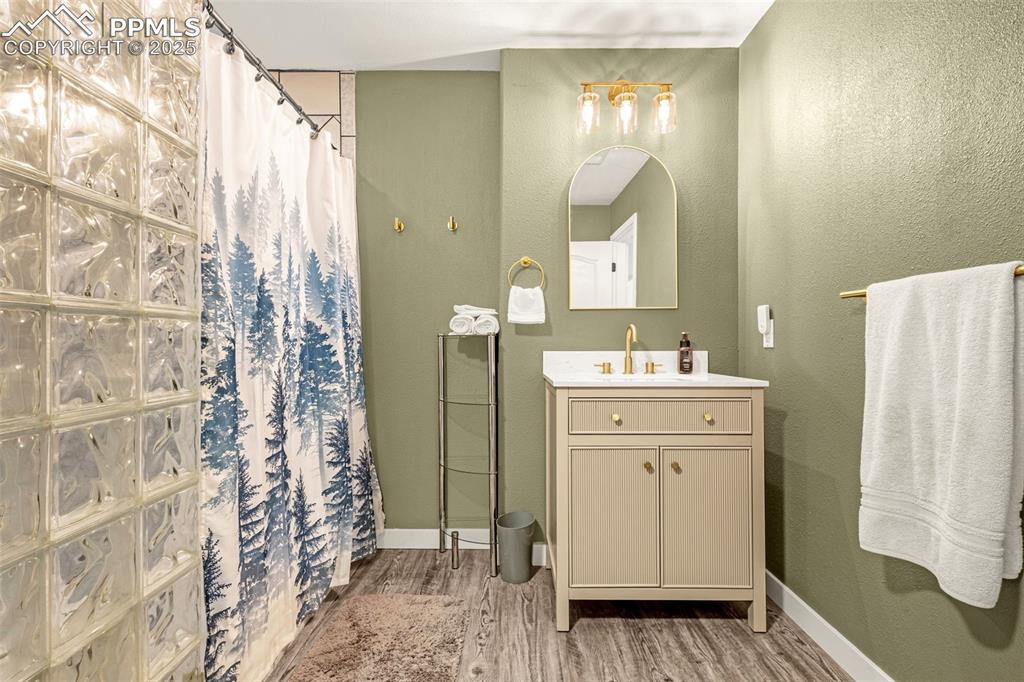 Image 15 of 17: Bathroom with baseboards, a shower with shower curtain, and wood finished f