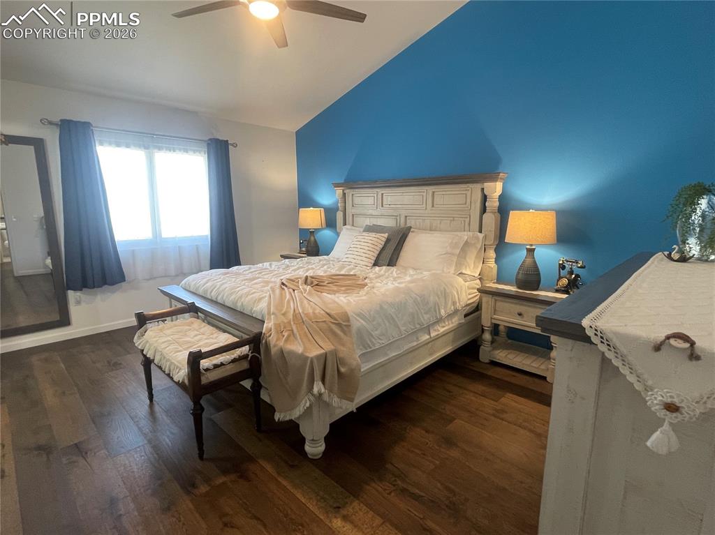 Image 10 of 19: Bedroom featuring dark wood-style floors, vaulted ceiling, and a ceiling fa