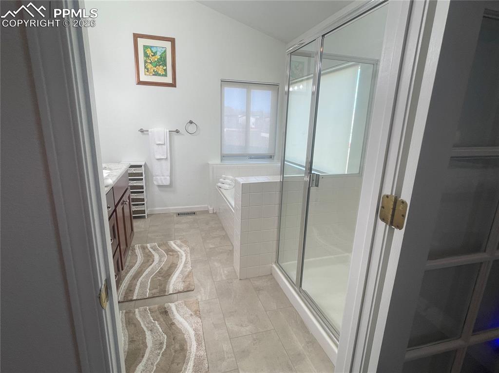 Image 11 of 19: Bathroom with vanity, a stall shower, a bath, and lofted ceiling