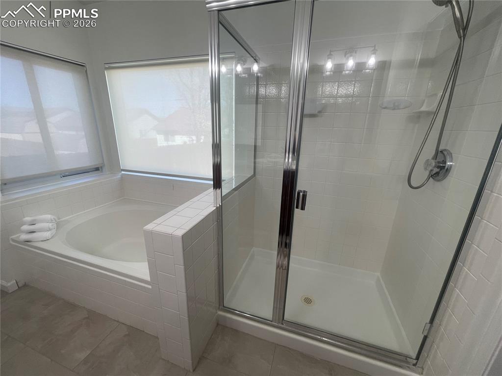 Image 12 of 19: Bathroom with a shower stall and a bath