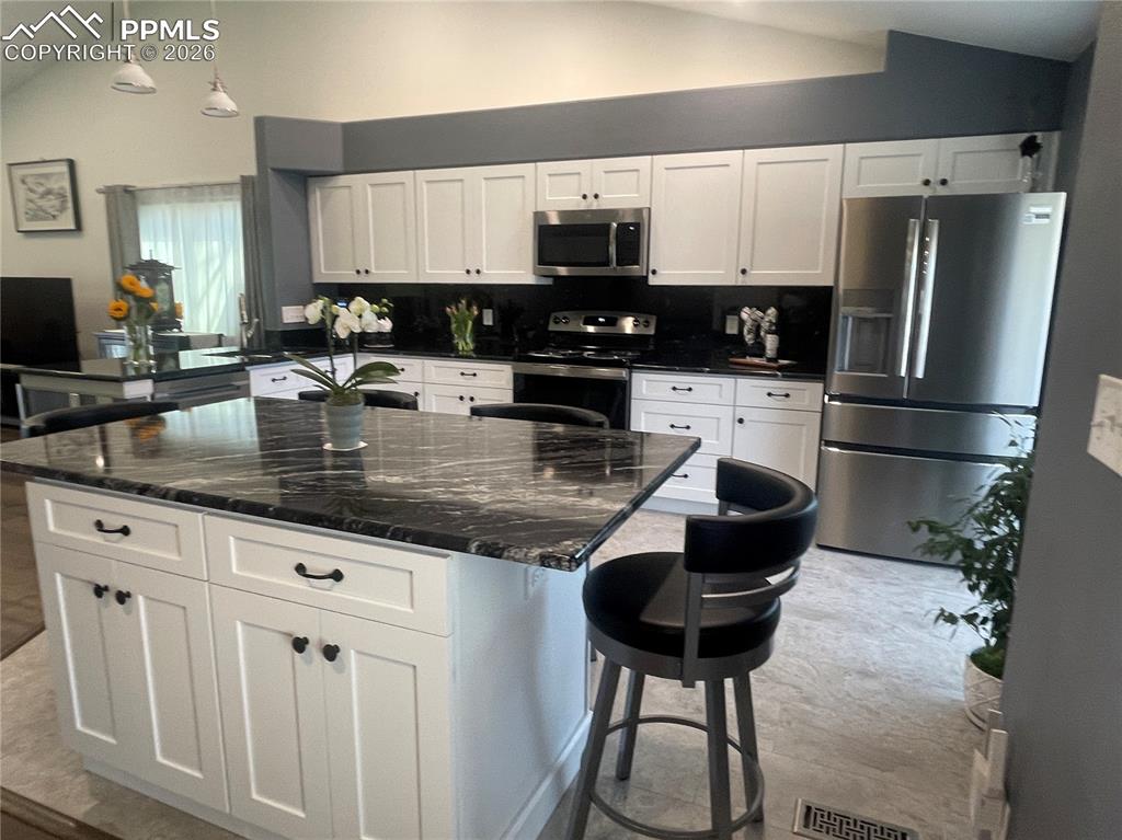 Image 3 of 19: Kitchen with lofted ceiling, stainless steel appliances, a kitchen breakfas