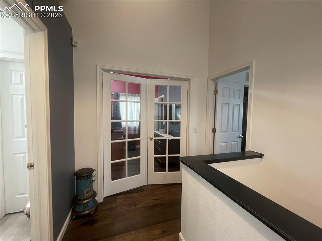 Image 8 of 19: Hallway with french doors, dark wood finished floors, and a high ceiling