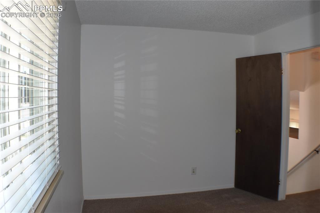 Image 16 of 40: Empty room featuring dark carpet and a textured ceiling