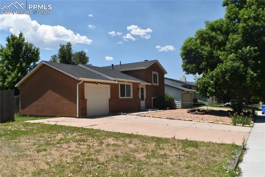 Image 2 of 40: Split level home featuring an attached garage, driveway, brick siding, and 