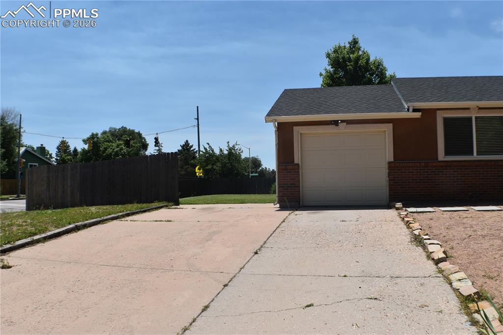Image 3 of 40: View of property exterior featuring driveway, brick siding, a garage, roof 