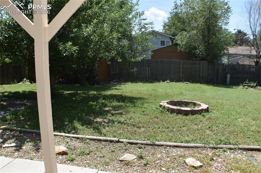 Image 30 of 40: Fenced backyard with a fire pit