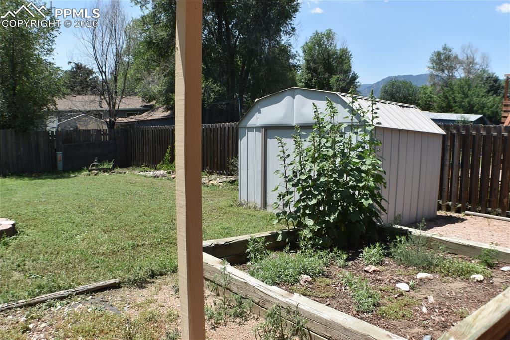 Image 33 of 40: Fenced backyard with a storage unit