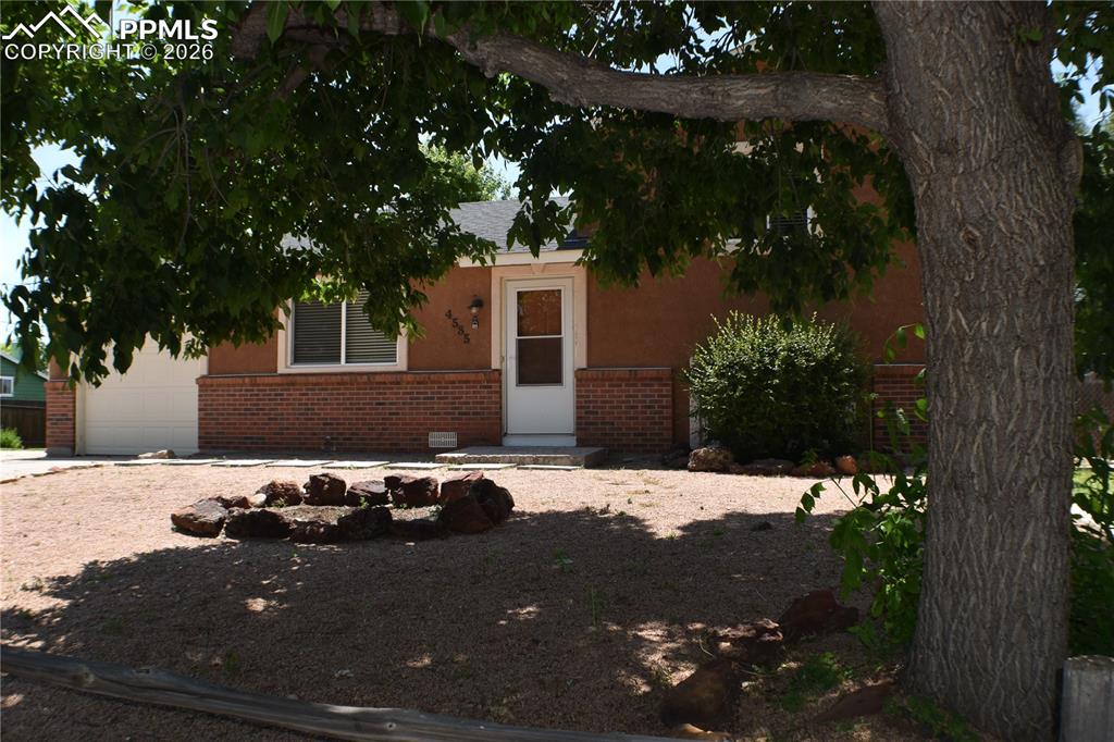 Image 39 of 40: View of property hidden behind natural elements with brick siding, an attac