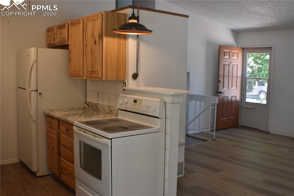 Image 7 of 40: Kitchen with white appliances, dark wood-type flooring, tasteful backsplash