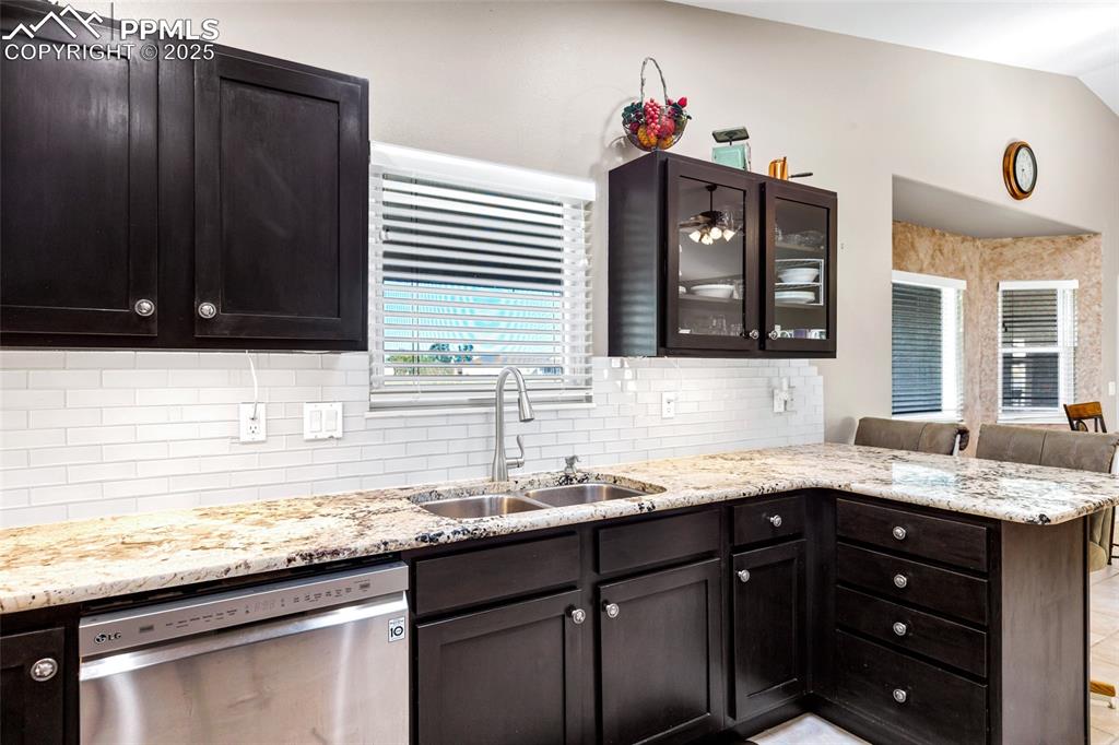 Image 11 of 44: Kitchen with stainless steel dishwasher, a peninsula, decorative backsplash