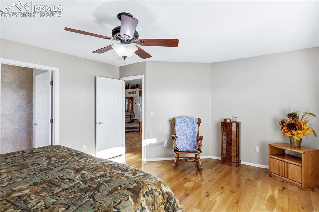 Image 13 of 44: Bedroom with light wood finished floors and ceiling fan