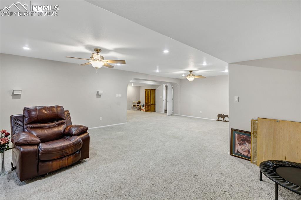 Image 26 of 44: Living area featuring ceiling fan, arched walkways, carpet floors, and rece