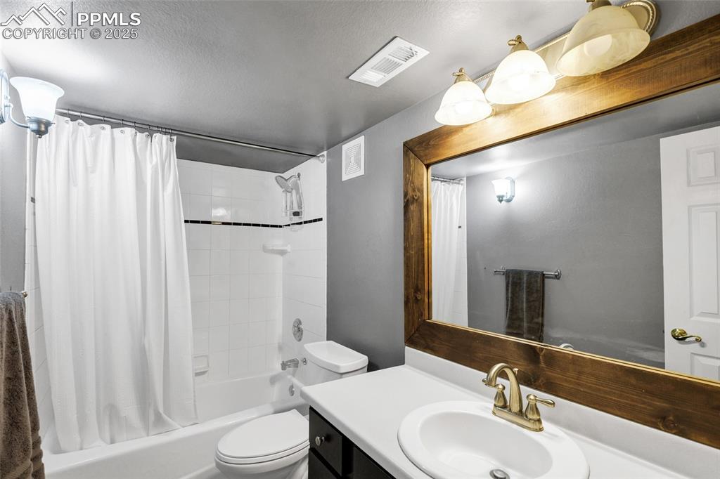 Image 30 of 44: Bathroom with vanity, shower / bath combo, and a textured ceiling