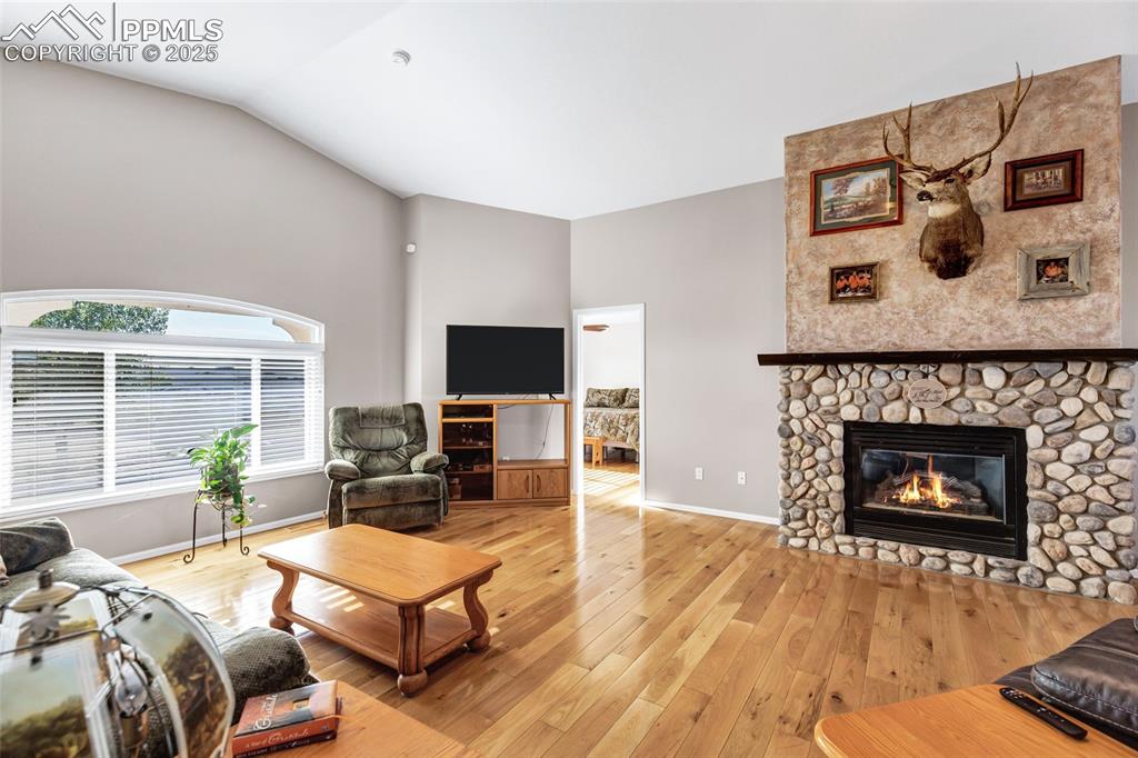 Image 6 of 44: Living area featuring lofted ceiling, light wood finished floors, and a sto
