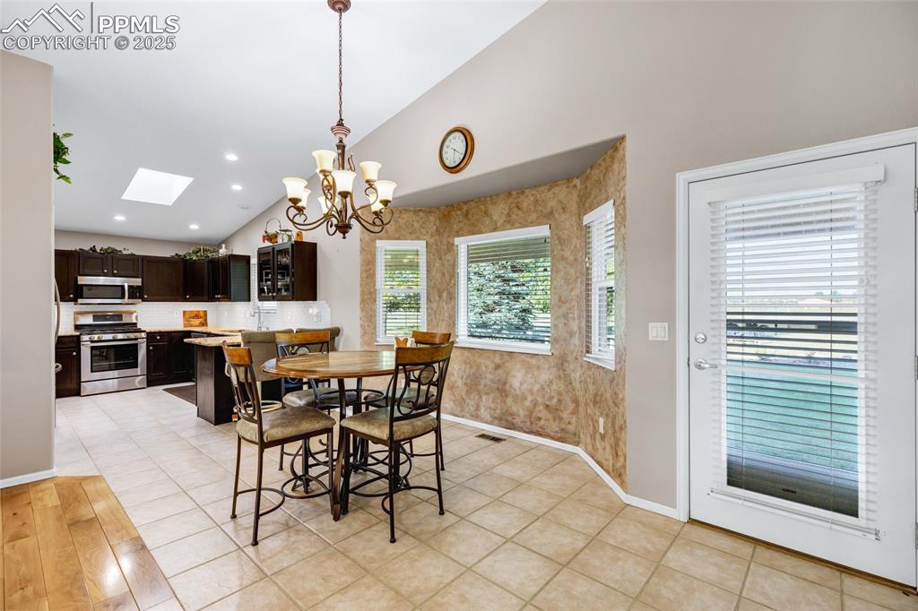 Image 7 of 44: Dining room with a chandelier, a skylight, and high vaulted ceiling