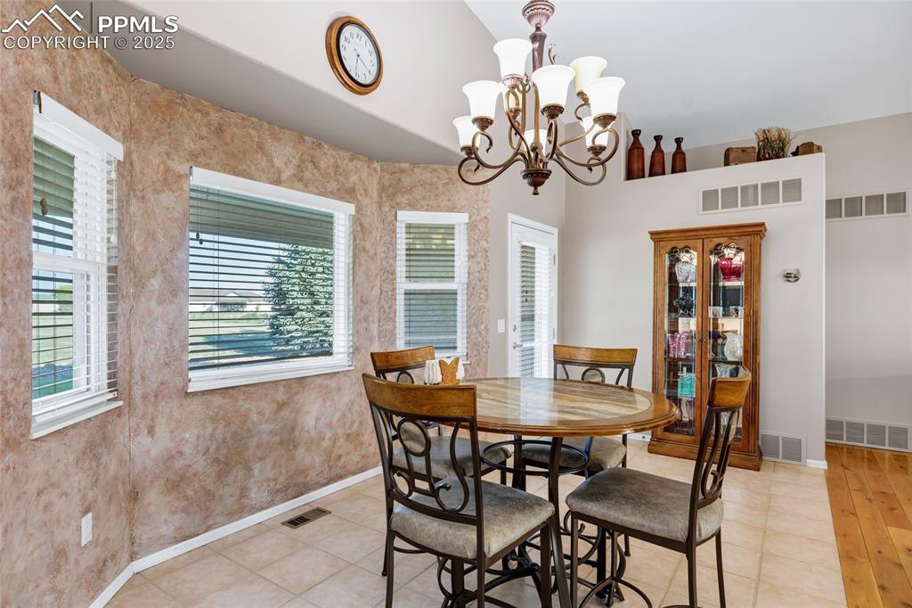 Image 8 of 44: Dining area featuring a chandelier, vaulted ceiling, and light tile pattern