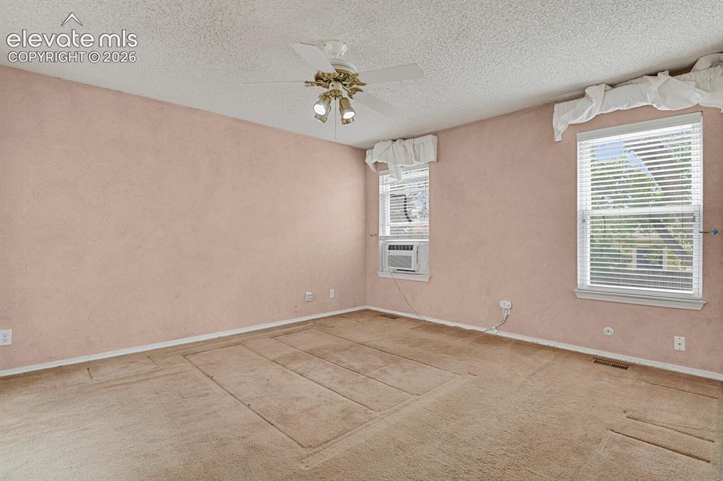Image 10 of 48: Spacious room featuring textured walls, two windows with blinds, a ceiling 