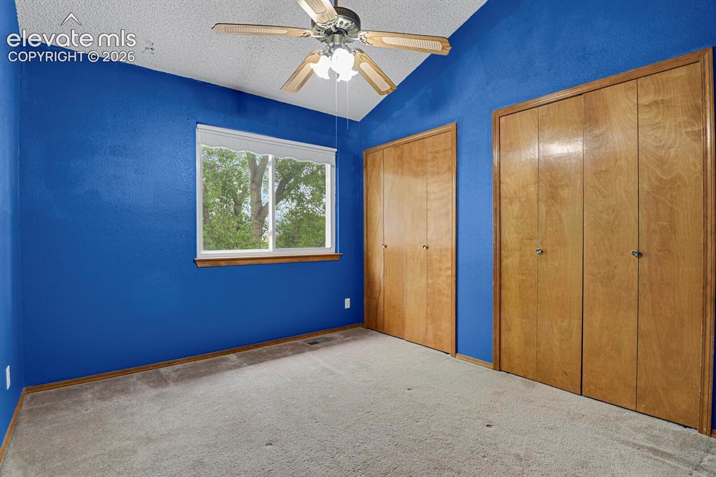 Image 14 of 48: Carpeted interior space featuring a window with a white blind, a ceiling fa