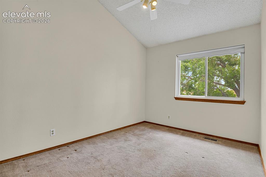 Image 17 of 48: Interior room featuring a vaulted ceiling and a ceiling fan with integrated