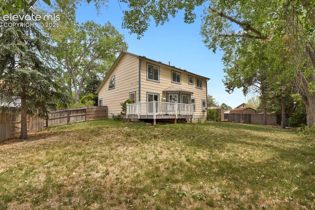 Image 29 of 48: Spacious rear yard with a multi-level wood deck, a bay window, and mature p