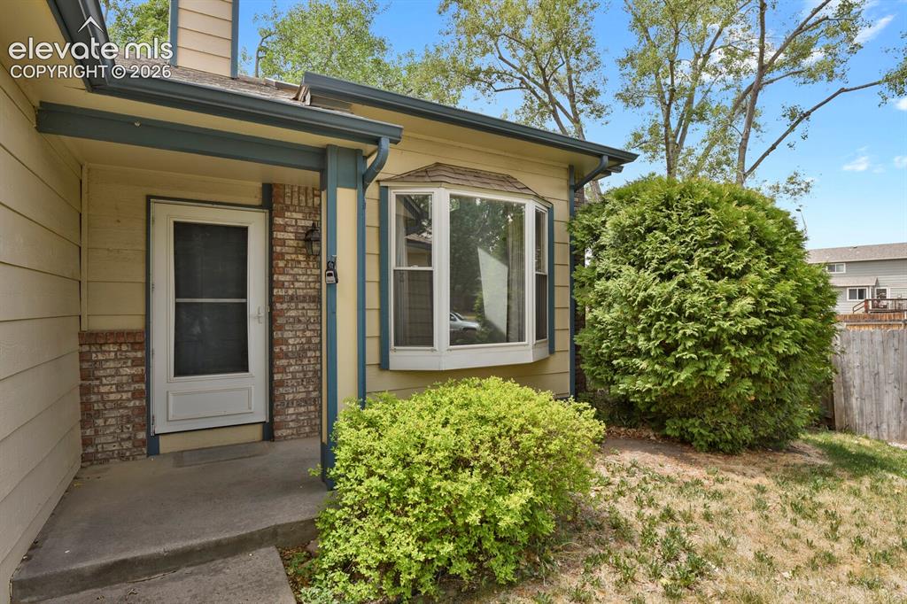 Image 3 of 48: Front entrance with a bay window, brick accents, and a screen door