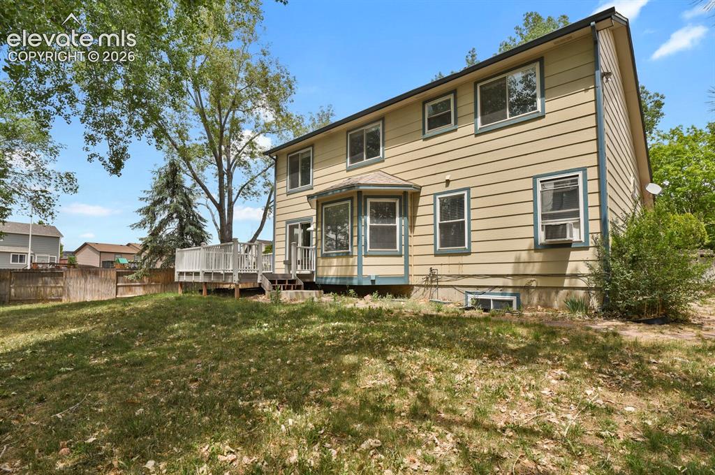 Image 30 of 48: Expansive rear yard featuring a multi-level wood deck, mature trees, and a 