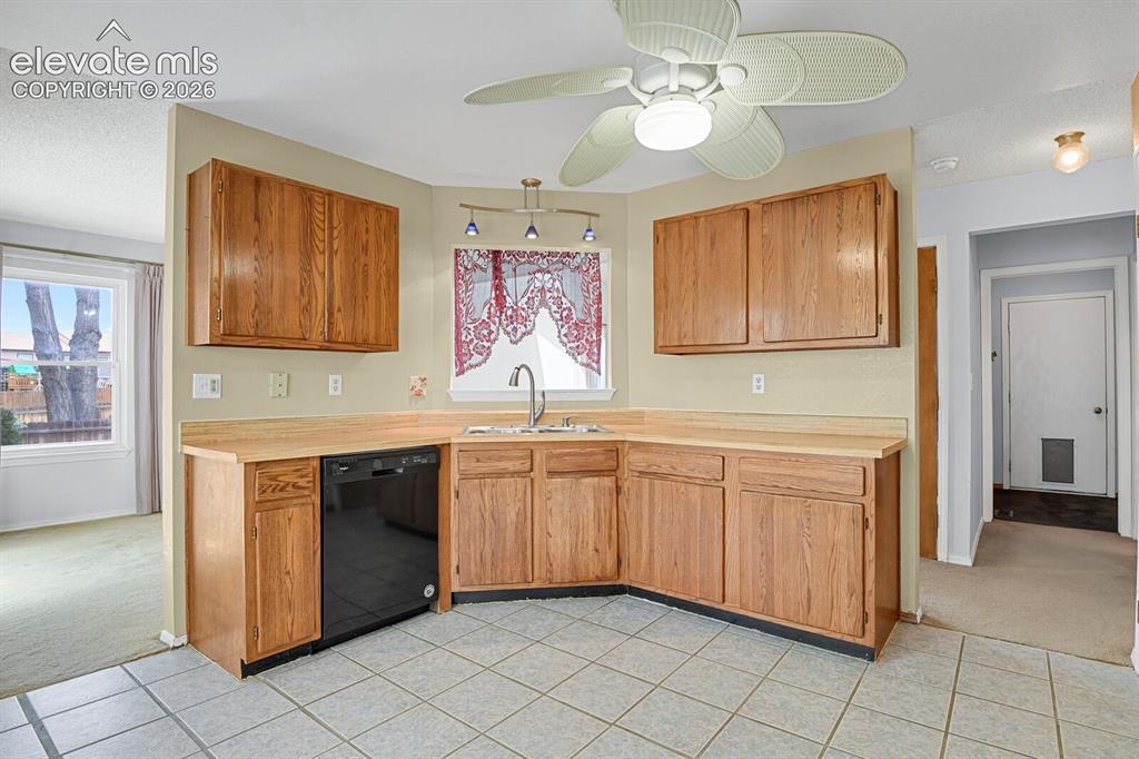 Image 38 of 48: Kitchen featuring light wood cabinetry, light-toned countertops, and a blac