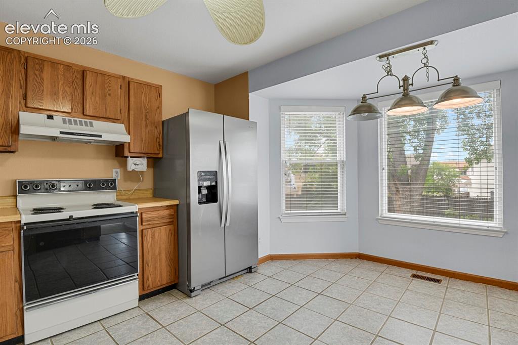 Image 39 of 48: Kitchen featuring a stainless steel side-by-side refrigerator, white range,