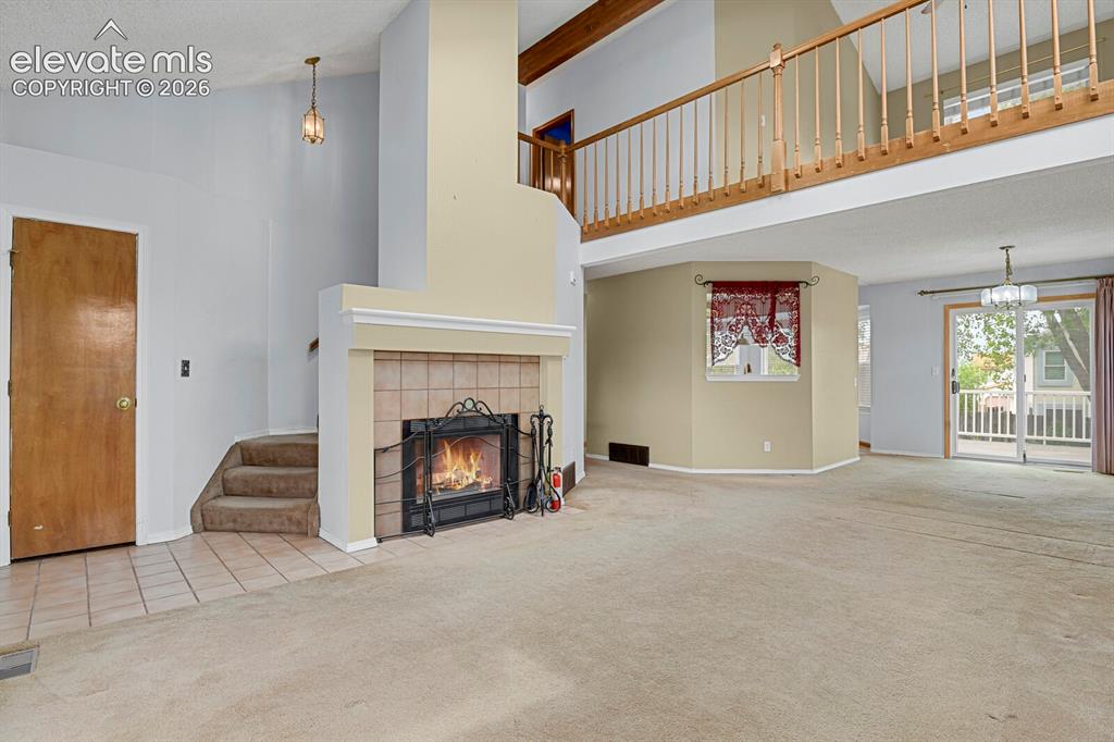 Image 4 of 48: Spacious living area featuring a tile-surround fireplace with hearth, a woo