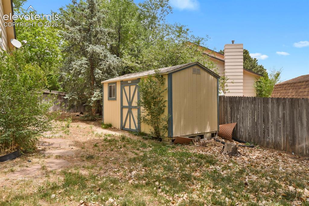Image 41 of 48: Detached storage shed with a window, positioned within a fenced yard featur