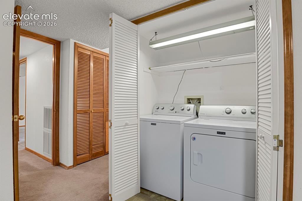 Image 42 of 48: Dedicated laundry closet featuring a built-in shelf, overhead fluorescent l