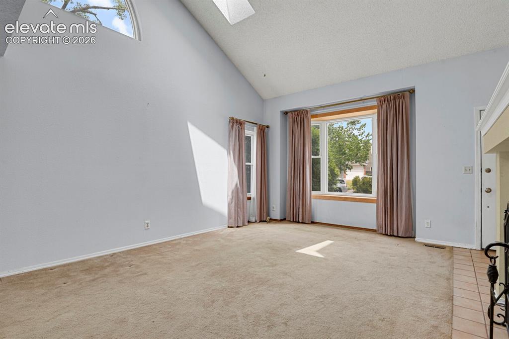 Image 43 of 48: Vaulted ceiling with an arched window and a skylight, complemented by a bay