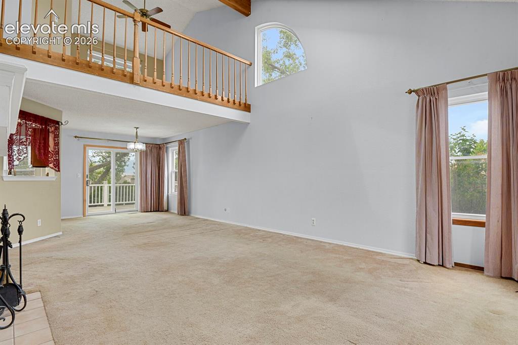 Image 44 of 48: Spacious living area featuring a vaulted ceiling with exposed wood beams, a